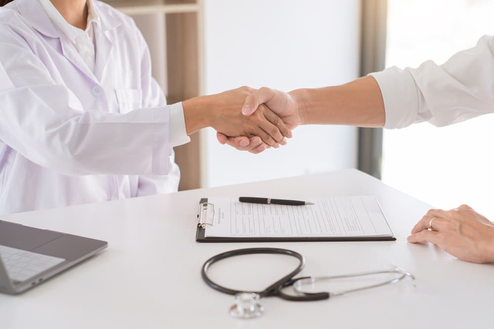 A doctor and patient shaking hands, symbolizing encouragement, empathy, and medical assistance.