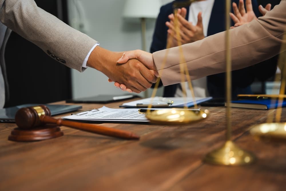 Justice and law concept: a team of judges in a courtroom working with a gavel and a digital tablet on a wooden table in sunlight.