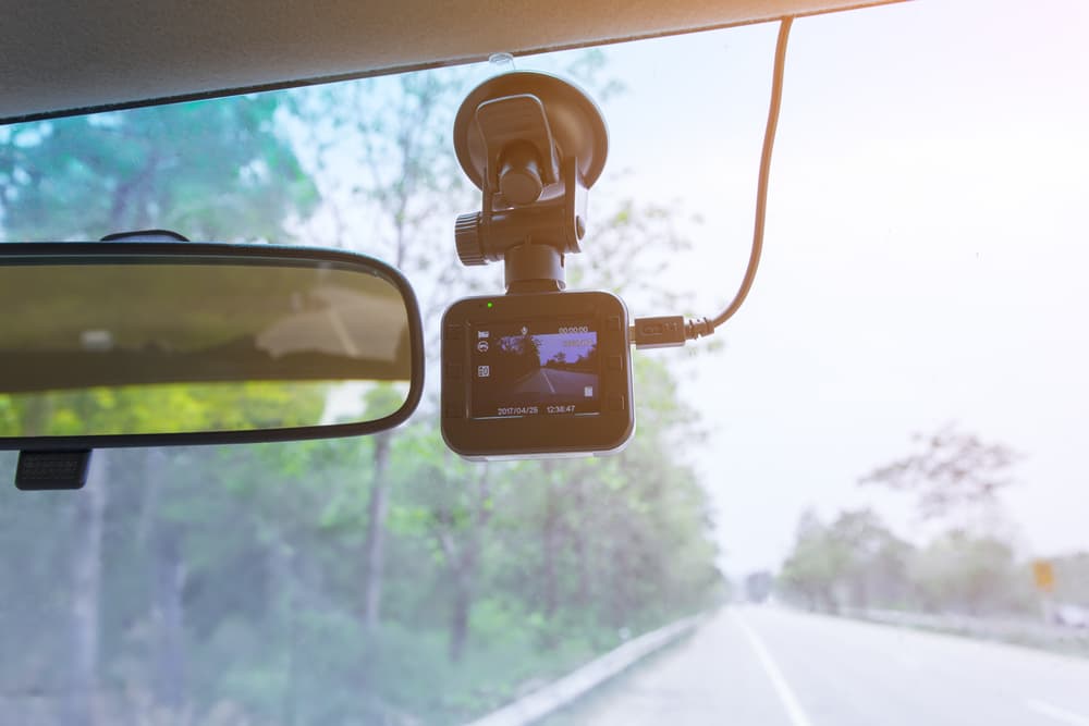 Dashboard camera installed on the windshield of a truck, recording video for evidence during a road trip or highway travel.