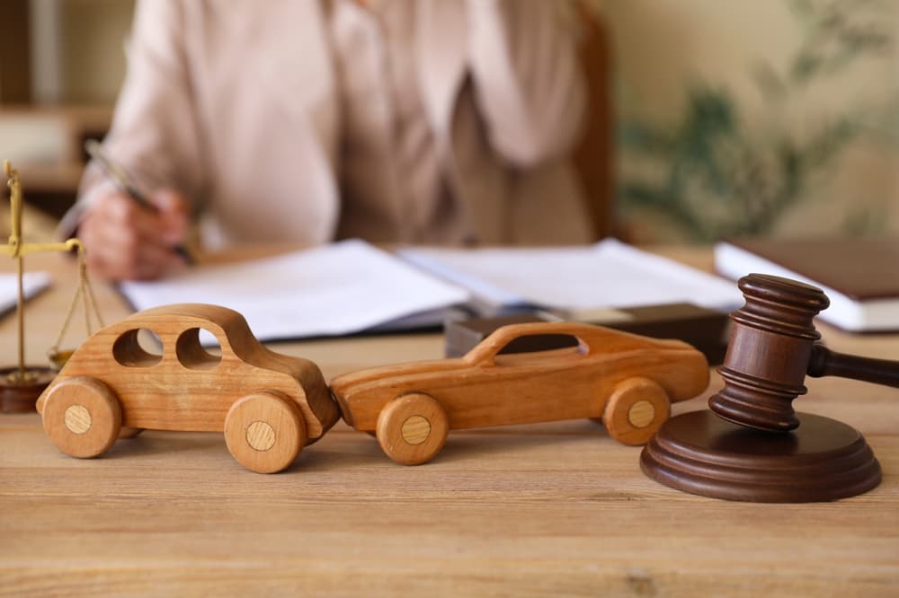 Close-up of a judge's gavel and wooden car models on a lawyer's desk in an office.






