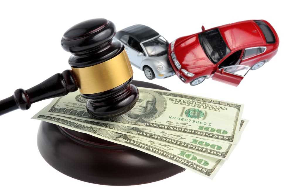 Judge's gavel with money and toy cars against a white background.






