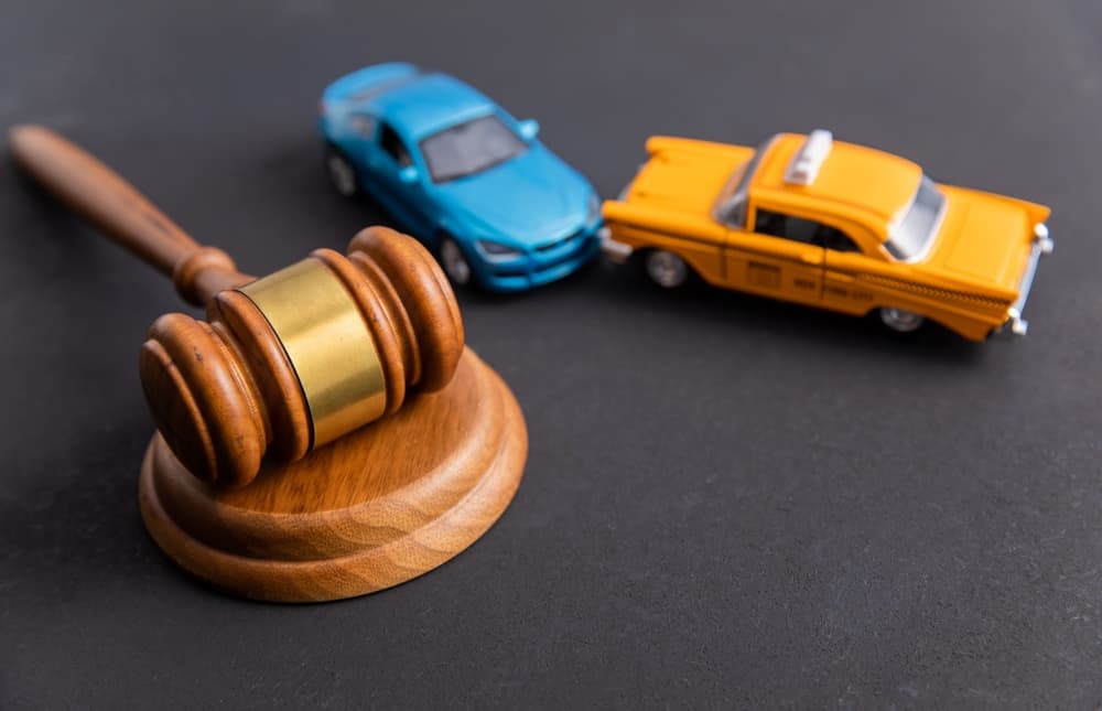 The image of the judge's gavel next to two cars involved in a collision, symbolizing the legal aspect of a traffic accident.