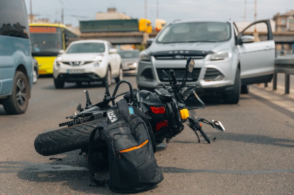 A motorcycle lying on a busy road after a collision highlights the need for legal support.