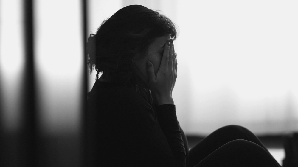 Grieving woman sitting with her face in her hands after losing a loved one