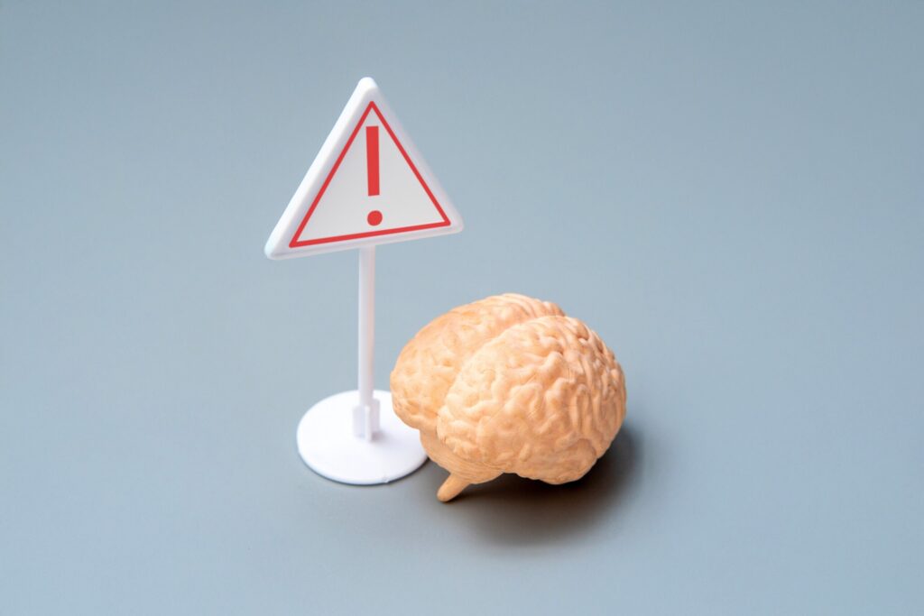 A brain model beside a warning sign representing traumatic injury claims handled by Dade City wrongful death lawyers.